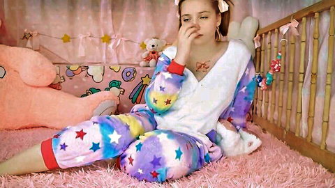 Littlekiwi in colorful star pajamas sitting in playful nursery, hand to face