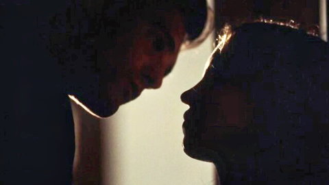 Silhouette of young couple leaning in for intimate kiss with profiles close together