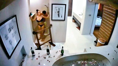 Wet babe in black lingerie showering in luxury bathroom with champagne bottles and rose petal tub