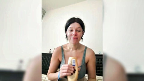 SexySophiaax teasing in low-cut tank top holding oil bottle