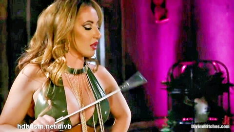 Blonde dominatrix in green latex harness with riding crop in BDSM femdom pose