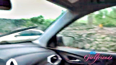 Car dashboard interior with scenic green landscape outside and Girlfriends watermark