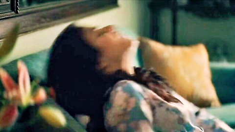 Steamy South Asian Indian woman lying back on couch with head tilted in ecstasy showing cleavage