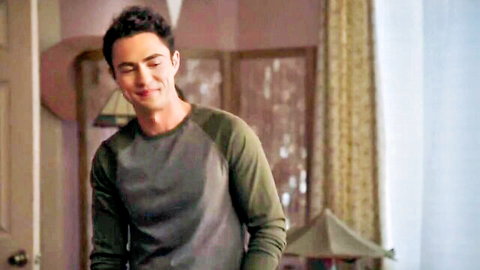 Handsome young man with curly hair smirks in bedroom, American Pie style