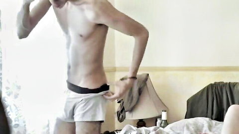 Slim shirtless man in white underwear adjusting in bedroom, toned body tease