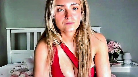 Blonde big tits beauty in red low-cut dress teases deep cleavage on bedroom webcam