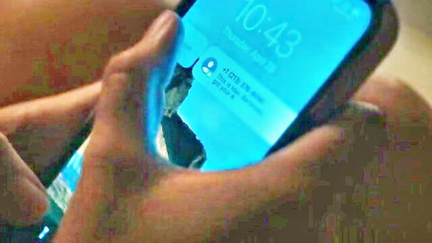 Close-up hand gripping smartphone screen showing blue-lit chat at 10:43
