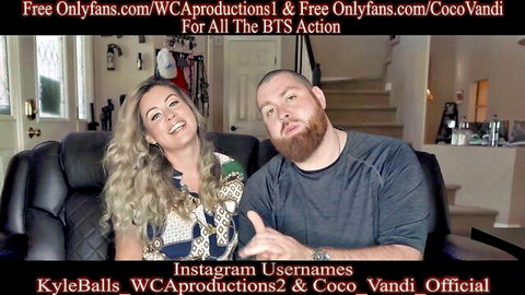 Smiling blonde MILF Coco Vandi and bearded stud posing together on couch in sexy BTS promo