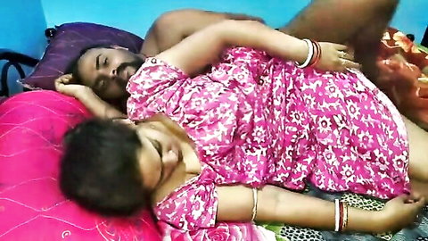 Desi Indian couple cuddling intimately in bed, her in pink floral dress