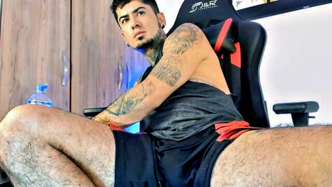 Tattooed muscular Kevin Morton1 lounging in tank top and shorts on Chaturbate