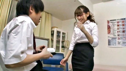Japanese teacher in uniform smiling at student with glasses in classroom