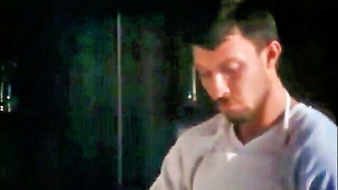 Intense male pornstar in white shirt, gazing down in dim light from Xtime.tv Vol. Ten