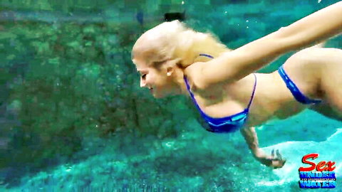 Busty blonde model in blue bikini diving underwater during training