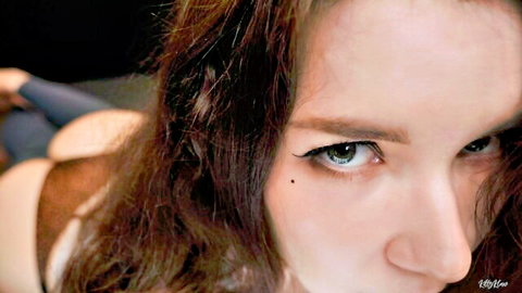 Seductive brunette girlfriend with intense green eyes and deep cleavage stares hungrily at camera