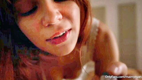 Close-up of sexy redhead with glossy parted lips and teeth visible teasing oral sex