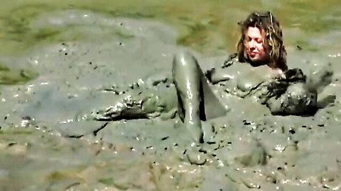 Mud-covered curvy babe lounging nude in steamy wild mud bath