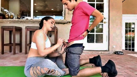 Brunette MILF in yoga gear kneels to stroke stepson's hard cock outdoors