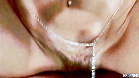 Closeup of shiny shaved wet pussy with gold necklace dangling over mound and navel piercing