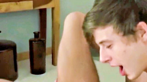 Young handsome guy smiling while giving oral to his friend's cock