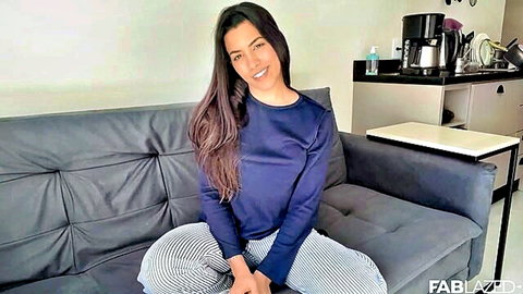 Smiling Latina woman in sweater and pants, teasing solo masturbation