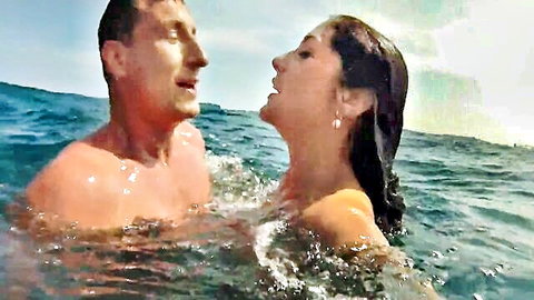 Brunette with long hair passionately kissed by hunk in ocean waves outdoor tease