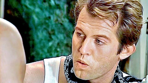 Vintage brunette stud in tank top and bandana with intense squinting gaze and open mouth