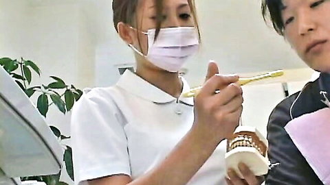 Japanese dentist in uniform with mask holding toothbrush over patient