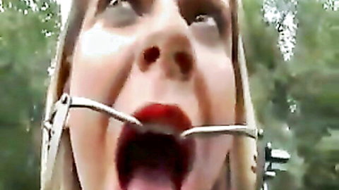 Blonde babe's mouth stretched wide open by BDSM ring gag outdoors