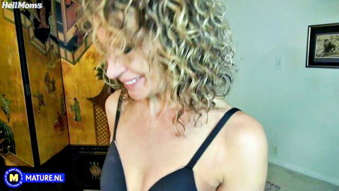 Mature blonde mom in black bra smiling during solo kink play