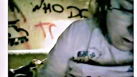 Bearded man with glasses in white shirt against graffiti wall, mouth open