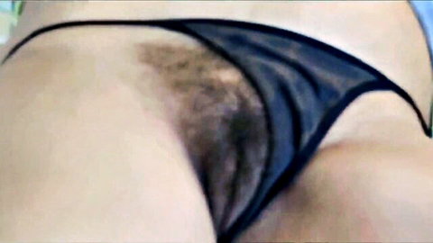 Hairy pussy peeking through sheer black thong panties closeup
