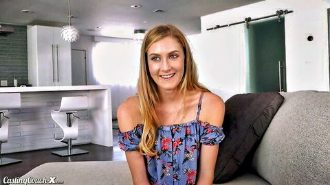 Blonde Jenni Jordan smiling in floral off-shoulder dress on casting couch