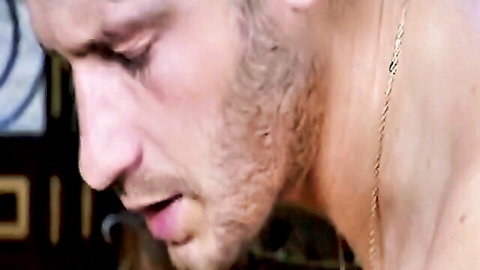 Close-up of handsome bearded man with gold chain necklace gazing intensely with open mouth