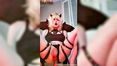 Blonde trans devil cosplayer in harness spreads legs exposing erect cock and balls