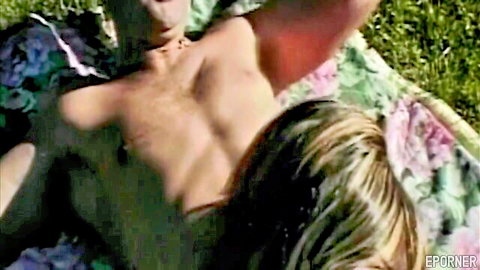 Blonde woman straddling naked man in outdoor cowgirl sex on sunny grass