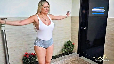 Monique Fuentes posing seductively in white tank top and gray shorts