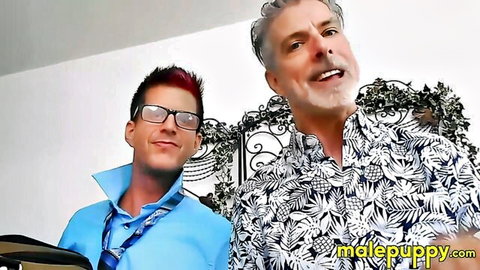 Gay DILF in Hawaiian shirt poses smiling with redhead glasses twink in blue shirt