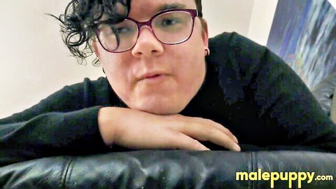 Curly-haired model in glasses and black top leaning seductively for Man Puppy fetish video