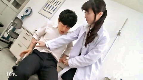 Japanese doctor in white coat examines young male patient's arm in clinic exam room