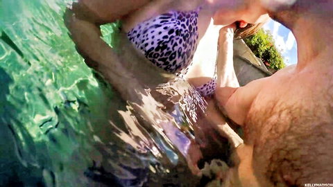 Busty brunette in leopard bikini kissing bearded man in pool with wet cleavage spilling out