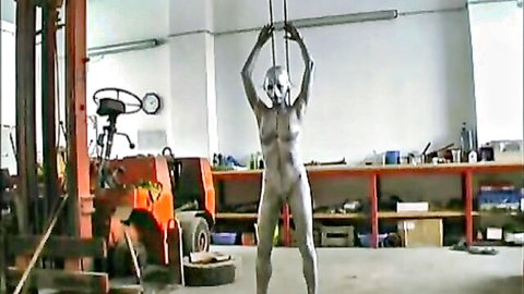 Silver body-painted sexy robot woman posing nude in workshop