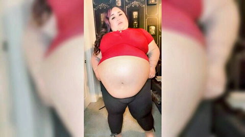 SSBBW in tight red top and black pants, showcasing large belly and curves