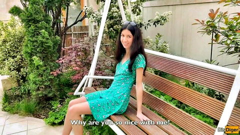 Smiling Asian woman in green floral dress on outdoor swing