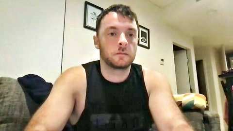Muscular bearded young man in tight black tank top on webcam solo