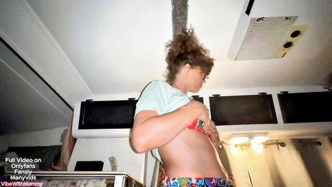 Curly haired woman lifts teal shirt exposing her bare perky tits in kitchen POV