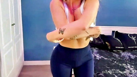 Tattooed blonde babe with cleavage in white top and tight blue leggings