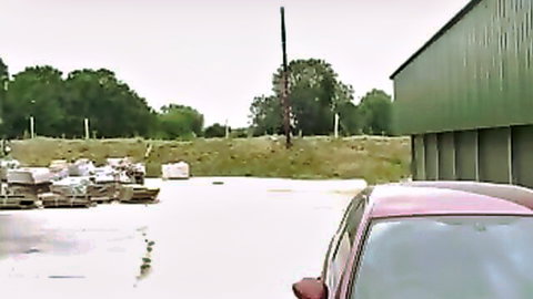 Pink car parked in outdoor yard near green barn and stacked pallets