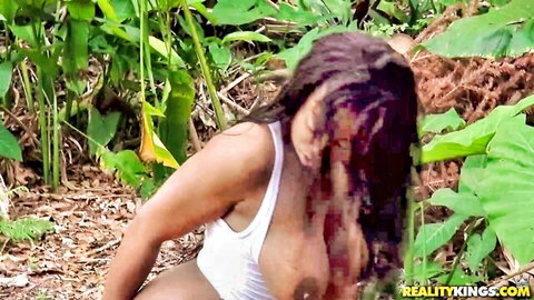 Wet ebony babe's massive tits visible through soaked white tank top in jungle