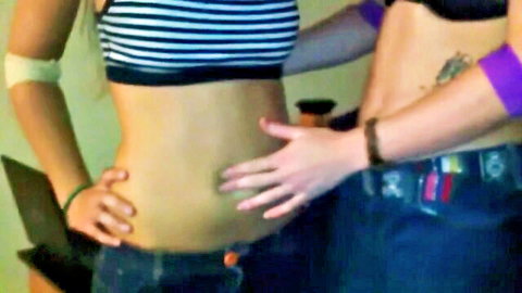 Two slim women in tank tops and jeans engage in intimate belly touching, homemade fetish play