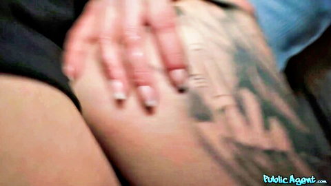 Woman's manicured hand grips tattooed man's thigh in blurry closeup